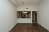 This well-appointed 2-bedroom, 2-bathroom single-floor residence offers a thoughtfully designed open-concept layout that maximizes both space and functionality. The interior is anchored by rich hardwood-style flooring that flows seamlessly throughout the main living areas, complementing the clean, modern aesthetic of the home.

The kitchen is a standout feature, showcasing sleek white cabinetry, dark contrast countertops, and a full suite of stainless steel appliances, including a refrigerator, range, and microwave. A breakfast bar peninsula provides both additional prep space and a natural dividing point between the kitchen and the adjacent living and dining areas. An elegant chandelier overhead adds a refined touch to the open dining space, enhancing the overall ambiance.

The bright, white walls and contemporary lighting fixtures throughout contribute to a crisp, airy atmosphere. Additional features include a frosted glass interior door that adds a charming architectural detail, along with visible ceiling vents that ensure comfortable climate control.

The two bedrooms offer comfortable retreats, while the two full bathrooms provide convenience for both residents and guests. The single-floor layout ensures easy, accessible living with a cohesive flow from room to room, making this a practical and stylish home.