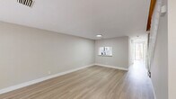 Located at 1495 Spring Harbor Dr in Delray Beach, Florida, this two-story home offers 2 bedrooms and 2 bathrooms thoughtfully distributed across two levels. The main floor hosts the open-concept living room and kitchen, finished with light wood-tone luxury vinyl plank flooring and neutral warm-gray walls that create a bright, clean aesthetic throughout. The kitchen has been updated with crisp white shaker cabinetry, a white subway tile backsplash, light quartz countertops, stainless steel appliances including a refrigerator, range, microwave, and dishwasher, and a single-basin stainless sink. A pass-through window connects the kitchen to the living area, enhancing the open feel. The spacious living room receives natural light from a large window and provides generous room for various layout configurations. Upstairs, the generously sized primary bedroom features vaulted ceilings, a ceiling fan, a window with outdoor views, and dual closets with built-in shelving — offering ample storage. The bathrooms are clean and functional, featuring a full tub-shower combo with white tile surround and brushed nickel fixtures. A staircase with a white balustrade connects the two floors, adding a classic touch to the home's contemporary interior.