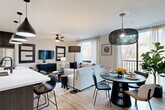 Located in Atlanta's vibrant Grant Park neighborhood, this thoughtfully designed 2-bedroom, 2-bathroom residence offers a seamless blend of modern style and functional living. The open-concept main living area unifies the kitchen, dining, and living spaces under one flowing layout. The kitchen is a standout, featuring dark wood cabinetry, stainless steel appliances, a large island with a white quartz countertop, and a trio of striking black pendant lights overhead. Light wood-style flooring runs throughout, complementing the neutral color palette accented by bold dark wall panels and geometric design details. The living room is bathed in natural light from large windows framing lush tree canopy views, with a ceiling fan adding comfort. The dining area features a sculptural woven pendant light and balcony access. Both bedrooms are well-proportioned, each with ceiling fans, ample closet space, and generous windows overlooking greenery. The primary bedroom includes a dedicated accent wall. The bathrooms are finished with clean white tile and a contrasting dark tile surround in the tub-shower. Additional conveniences include a pantry, laundry, utility room, and multiple closets throughout.