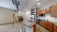 Located at 800 Lake Carolyn Pkwy in Irving, TX, this two-bedroom, two-bathroom residence offers a well-designed single-floor layout with a blend of industrial and modern finishes. The open-concept kitchen is a standout, featuring warm wood cabinetry, granite countertops, a subway tile backsplash, and a full suite of stainless steel appliances including a French door refrigerator, dishwasher, and built-in microwave. A curved granite-topped island with a cooktop serves as both a functional workspace and a natural divider between the kitchen and living areas. Polished concrete floors run throughout the main living spaces, complemented by exposed ductwork that adds an industrial character to the high ceilings. Track lighting and pendant fixtures provide ample illumination. A built-in desk nook offers a convenient workspace off the main living area. Both bedrooms are carpeted and filled with natural light from large windows. The spacious primary bedroom includes a walk-in closet with wire shelving and an en-suite bathroom featuring a dual-sink granite vanity and a glass-enclosed walk-in shower. A second full bathroom and a dedicated laundry area complete this thoughtfully laid-out residence. Two patio spaces provide additional outdoor living options.