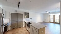 Located at 8700 Seeing Trail Rd in Wake Forest, NC, this well-appointed 2-bedroom, 2-bathroom residence offers a thoughtfully designed single-level layout. The open-concept living and dining area features warm hardwood-style flooring and track lighting, creating a bright and inviting atmosphere. French doors lead to a private balcony, filling the space with natural light and outdoor views.

The kitchen serves as a central hub, showcasing granite countertops, a large center island with a farmhouse-style sink, glass-front upper cabinets, white subway tile backsplash, and a full suite of stainless steel appliances. A convenient built-in desk with granite surface and open shelving adds functional workspace to the living area.

Both bedrooms are carpeted and include ceiling fans. The generously sized primary bedroom benefits from dual windows with outdoor views and access to a walk-in closet outfitted with extensive wire shelving. The bathrooms are finished with granite vanity tops, gray shaker-style cabinetry, lighted mirrors, and glass-enclosed showers. A dedicated laundry room with hardwood-style flooring and wire shelving provides added convenience. Four closets throughout offer ample storage throughout this well-equipped residence.