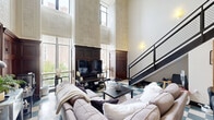 Located in downtown Winston-Salem, this two-story, 2-bedroom, 3-bathroom residence masterfully blends historic architectural character with modern updates. The main floor is anchored by a dramatic double-height living area, where soaring ceilings showcase ornate embossed wall panels, rich dark wood wainscoting, and an elegantly detailed tin ceiling with a decorative medallion. Tall windows flood the space with natural light and offer views of the surrounding cityscape. A bold checkerboard tile floor adds a striking visual element throughout the main level, which also includes an open kitchen outfitted with dark cabinetry, stainless steel appliances, and stone countertops. A sleek, industrial-style open staircase with a metal mesh railing leads to the upper level. The two bedrooms are comfortably sized, featuring light wood flooring, modern wood-tone doors with black trim accents, and ample closet space. One bedroom includes a horizontal clerestory window, bringing in additional natural light. The three bathrooms are clean and functional, with one featuring a contemporary glass-top vanity. The overall ambiance balances the grandeur of historic architecture with the practicality and style of a thoughtfully updated urban residence.