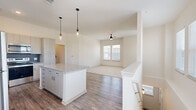 This two-story home offers a thoughtfully designed layout across two levels, with the main living spaces occupying the upper floor and an attached garage at ground level. The garage is equipped with an automatic opener and provides clean, functional storage and parking space.

The main floor centers around an open-concept kitchen and living area bathed in natural light. The kitchen is a standout feature, showcasing granite countertops, a central island with pendant lighting, light wood cabinetry, a navy blue subway tile backsplash, and a full suite of stainless steel appliances. Wood-look flooring flows through the kitchen and living room, where a ceiling fan and bright windows create a comfortable, airy atmosphere.

The two bedrooms are carpeted for warmth and comfort, each offering ample natural light through large windows with blinds. The primary bedroom includes a walk-in closet with wire shelving and access to a private outdoor balcony via sliding glass doors. Both bathrooms are finished with granite-topped vanities, light wood cabinetry, and tub-shower combinations. Two hallways and additional closets provide convenient storage throughout. The home's neutral color palette and modern finishes give the entire space a clean, contemporary feel.