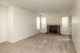 Located at 6210 Meadow Crest Dr in Johnston, Iowa, this one-bedroom, one-bathroom residence offers a well-organized single-floor layout designed for comfortable everyday living. The combined kitchen and living room serves as the heart of the home, where the living area features plush wall-to-wall carpeting, a ceiling fan, multiple windows that invite natural light, and a standout brick fireplace that adds warmth and character. French doors lead to the exterior, further brightening the space. The kitchen is efficiently arranged in a galley style, equipped with cream cabinetry accented by wood trim, granite-look countertops, tile flooring, and white appliances including a refrigerator, dishwasher, stove, and built-in microwave. A double-basin sink sits beneath a window overlooking the outdoors. The bedroom offers a cozy carpeted retreat with a natural window and access to a dedicated closet. The full bathroom features tile flooring, a tub-shower combination with grab bars, a vanity with cabinet storage, and clean, neutral finishes throughout. A hallway connects the private areas of the unit seamlessly. The overall aesthetic is light and neutral, creating a bright, move-in-ready environment suited for a range of lifestyles.