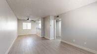 Located at 1333 N Dysart Rd in Avondale, Arizona, this efficiently designed single-floor unit offers a clean, modern aesthetic with a neutral color palette and cohesive finishes throughout. Light luxury vinyl plank flooring runs continuously across the space, complementing the soft gray walls and bright white trim.

The combined kitchen and living area forms the heart of the unit. The kitchen is outfitted with white shaker-style cabinetry accented by matte black hardware, granite-look countertops, and stainless steel appliances including a range, refrigerator, and built-in microwave. A window fitted with horizontal blinds brings in natural light, brightening the workspace. The adjacent living area is open and flexible, featuring a textured ceiling and a ceiling fan with an integrated light fixture, along with a window that further enhances natural illumination.

A hallway connects the main living space to the bathroom, which is finished with the same light flooring. The bathroom includes a white single-sink vanity with granite-look countertop, matte black fixtures and accessories, a toilet, and a full shower-tub combination enclosed by a curved rod. The overall ambiance of the unit is clean, contemporary, and move-in ready, reflecting modern design sensibilities suited to efficient urban living.
