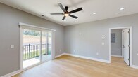 Located in Toccoa, GA, this thoughtfully designed single-story residence offers a modern aesthetic with clean lines and quality finishes throughout. The open-concept kitchen and living area serves as the heart of the home, featuring sleek white cabinetry extending to the ceiling, stainless steel appliances, and a generous quartz-topped island with an undermount sink — ideal for both everyday living and entertaining. Light hardwood flooring flows seamlessly throughout the entire space, enhancing the bright, cohesive feel. The spacious primary bedroom includes a ceiling fan, recessed lighting, and a sliding glass door that opens to an outdoor balcony with greenery views. A second bedroom offers a large window with natural light, a ceiling fan, and a built-in closet. Two well-appointed bathrooms feature white quartz countertops, white cabinetry with matte black hardware, and large mirrors, lending a crisp, contemporary finish. One bathroom includes a window for added ventilation and light. Neutral gray walls, white trim, and recessed lighting are consistent throughout, creating a clean, modern ambiance. A hallway with a pendant light connects the living spaces to the bedroom wing, completing this efficiently designed and move-in-ready home.