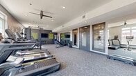 Located at 3700 Monument Avenue in Richmond, Virginia, this fitness center offers a thoughtfully designed exercise space across a single floor. The room is finished with durable carpet tile flooring in a neutral gray and yellow pattern, complemented by smooth white ceilings equipped with recessed lighting and ceiling fans for optimal air circulation and comfort during workouts.

The space is generously lined with large windows along multiple walls, allowing abundant natural light to fill the room and providing views of the surrounding neighborhood. Full-length mirrors on one wall visually expand the space and support proper form during training sessions.

Equipment is comprehensive and varied. Cardio offerings include multiple treadmills and a stationary bike, while strength training is supported by a power rack, adjustable weight bench, and a full dumbbell rack. Functional training options include a hanging heavy bag, medicine balls, stability balls, plyo boxes, and step platforms. A dedicated wall display features decorative vintage rackets alongside fitness accessories, adding a stylistic touch to the athletic environment.

The color scheme of charcoal gray, white, and yellow-green accents gives the fitness center a modern, energetic aesthetic. Multiple gray-framed glass doors provide entry and exit points, ensuring convenient access. Overall, this facility delivers a complete and well-organized training environment suited for a wide range of fitness activities.