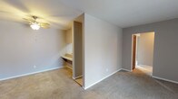 Located at 4427 Wilmington Pike in Dayton, Ohio, this single-floor unit offers a practical and comfortable layout across several well-defined living spaces. The living room immediately draws attention with its striking exposed brick accent wall, warm wood-toned entry door, and a large sliding glass door fitted with vertical blinds that invites generous natural light into the carpeted space. Adjacent to the living area is a dining or flex room equipped with a ceiling fan and a built-in countertop desk — a functional architectural detail ideal for work or study. The kitchen is conveniently positioned nearby, featuring wood-toned cabinetry and essential appliances. The unit includes multiple bedrooms, each finished with neutral-toned carpet, soft gray walls, and white trim. The bedrooms benefit from multiple windows that allow natural light to filter in, and closets with louvered bi-fold doors provide ample storage. The bathroom features tile flooring, a wide vanity with a light countertop, a large mirror with overhead lighting, and a separate water closet area for added privacy. Throughout the unit, consistent neutral finishes and carpeted floors create a cohesive, move-in-ready atmosphere suited to a variety of lifestyles.