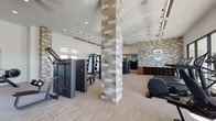 The Highwater Fitness Center is a thoughtfully designed, single-floor gym facility that blends upscale aesthetics with comprehensive workout functionality. Soaring ceilings create an open, airy atmosphere throughout the space, enhanced by abundant natural light streaming through large floor-to-ceiling windows and elevated clerestory windows along the perimeter walls.

The facility is anchored by a striking stacked-tile column that serves as a visual centerpiece, complemented by warm neutral tones, light wood-look flooring, and a textured mosaic tile accent wall featuring the Highwater branding logo. Pendant and linear track lighting add a modern, refined touch to the overall design.

Equipment is thoughtfully arranged across the space and includes a full suite of premium Technogym strength machines, a multi-station cable system, adjustable benches, and a dedicated free-weight zone stocked with dumbbells and kettlebells. A mirrored free-motion area provides ample space for functional training with medicine balls and plyo boxes. Cardio options include stair climbers, treadmills, ellipticals, and rowing machines, all positioned to take advantage of the expansive outdoor views through the large glass wall. Wall-mounted flat-screen televisions are integrated throughout, and built-in shelving provides convenient storage for personal belongings.