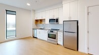Located on the third floor at 4603 Minnehaha Ave in Minneapolis, Minnesota, this thoughtfully designed unit offers a clean, modern aesthetic across a single-floor layout. Light-toned hardwood flooring runs throughout, lending warmth and visual continuity to the space.

The open living and kitchen area serves as the heart of the unit. The kitchen is outfitted with white flat-panel cabinetry, warm natural wood open shelving, a subway tile backsplash, gray quartz-style countertops, and a full suite of stainless steel appliances including a refrigerator, electric range, microwave, and dishwasher. Recessed lighting and windows allowing natural light keep the space feeling bright and airy.

A corridor connects the main living area to the private rooms, with convenient in-unit stacked laundry tucked just off the hallway. The bathroom features a full tub and shower combination with a curved curtain rod, clean white finishes, and light hardwood-style flooring consistent with the rest of the unit.

The living area is open and versatile, with crisp white walls, recessed lighting, and a window that brings in natural light. The overall design is minimal and contemporary, making efficient use of the available footprint while maintaining a comfortable and functional living environment.