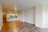 Located on the 24th floor at 1953 Westlake Ave in Seattle, this two-bedroom condo offers a well-designed open-concept layout finished with warm hardwood-style flooring throughout. The combined living, dining, and kitchen area forms the heart of the unit, where a peninsula with granite countertops separates the kitchen from the main living space. The kitchen is appointed with white shaker cabinetry, subway tile backsplash, stainless steel appliances, and recessed lighting, creating a clean, contemporary aesthetic. Large floor-to-ceiling windows flood the living area with natural light and open to a private balcony with sweeping views of the Seattle skyline. The primary bedroom is generously proportioned, featuring a large window with city views and access to a spacious walk-in closet with built-in shelving and hanging rods. The second bedroom also benefits from natural light and urban views. A hallway connects the private areas of the unit, leading to a well-appointed bathroom with a granite-topped vanity, white cabinetry, and large-format tile flooring. Three closets in total provide ample storage throughout. The unit's neutral palette and modern finishes create a bright, cohesive ambiance throughout.