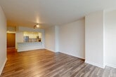 Located on the 24th floor at 1953 Westlake Ave in Seattle, this two-bedroom condo offers a well-designed open-concept layout finished with warm hardwood-style flooring throughout. The combined living, dining, and kitchen area forms the heart of the unit, where a peninsula with granite countertops separates the kitchen from the main living space. The kitchen is appointed with white shaker cabinetry, subway tile backsplash, stainless steel appliances, and recessed lighting, creating a clean, contemporary aesthetic. Large floor-to-ceiling windows flood the living area with natural light and open to a private balcony with sweeping views of the Seattle skyline. The primary bedroom is generously proportioned, featuring a large window with city views and access to a spacious walk-in closet with built-in shelving and hanging rods. The second bedroom also benefits from natural light and urban views. A hallway connects the private areas of the unit, leading to a well-appointed bathroom with a granite-topped vanity, white cabinetry, and large-format tile flooring. Three closets in total provide ample storage throughout. The unit's neutral palette and modern finishes create a bright, cohesive ambiance throughout.