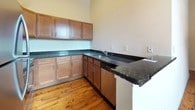 This single-floor, 2-bedroom, 2-bathroom residence offers a thoughtfully designed layout that balances functionality and comfort. The kitchen serves as a central highlight, featuring rich wood cabinetry, dark granite countertops, and warm-toned hardwood flooring that extends throughout the living areas. A peninsula with a matching granite surface provides additional workspace and a natural division between the kitchen and the adjacent living space. Stainless steel appliances, including a full-size refrigerator and built-in microwave, complete the kitchen's practical and contemporary appeal. Exposed structural beams add a subtle architectural character to the space.

The two bedrooms are generously proportioned, each showcasing the same rich hardwood flooring and neutral wall tones, offering a clean, versatile canvas for personalization. Both bathrooms are finished with a clean, functional aesthetic, each equipped with a full tub-and-shower combination, curved curtain rod, and brushed nickel fixtures and hardware. Light-toned tile flooring grounds the bathrooms with a crisp, coordinated look. Neutral wall colors throughout the residence create a cohesive, welcoming atmosphere that is both bright and easy to style.