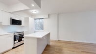 Located in Vancouver's vibrant West End neighbourhood, this one-bedroom, one-bathroom unit at 855 Jervis Street offers a thoughtfully designed layout with modern finishes throughout. Light-toned hardwood-style flooring runs continuously across the entire space, creating a cohesive and clean aesthetic.

The open-concept kitchen and living area forms the heart of the unit. The kitchen has been fully renovated with sleek white flat-panel cabinetry extending to the ceiling, a white quartz peninsula with generous prep space, and a full suite of stainless steel appliances including a refrigerator, dishwasher, electric range, and built-in microwave. The living area benefits from a large window with vertical blinds, allowing natural light to fill the room while offering views of surrounding greenery.

The bedroom is a well-proportioned retreat, featuring its own large window framing lush outdoor foliage and a baseboard radiator for comfortable heating. Three closets throughout the unit provide ample storage space, including a mirrored sliding-door closet visible from the hallway.

The bathroom is finished to a high standard, with white subway tile surrounding a soaking tub and shower, a white floating vanity with an undermount sink, chrome fixtures, an oval LED-lit mirror, and matching hardwood-style flooring. Clean white walls and recessed lighting complete the bright, contemporary feel of this well-appointed unit.