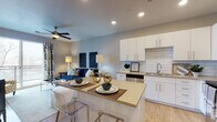 Located at 435 E 400 S in Salt Lake City, Utah, this single-floor residence offers a thoughtfully designed layout with modern finishes and a cohesive aesthetic throughout. The open-concept kitchen and living area serves as the central hub of the unit, where light wood-style flooring, recessed lighting, and a ceiling fan contribute to a bright and comfortable atmosphere. The kitchen is well-equipped with white shaker-style cabinetry, subway tile backsplash, stainless steel appliances including a refrigerator, electric range, microwave, and dishwasher, and a neutral-toned countertop that extends to a peninsula with bar seating. The adjoining living area features a sliding glass door that opens to a private balcony, allowing natural light to fill the space and providing outdoor views of the surrounding neighborhood.

The bedroom is a tranquil retreat featuring plush carpeting, large windows with city views, and ample natural light filtered through sheer curtains. The bathroom is cleanly finished with wood-look tile flooring, a white vanity with gray countertop, and a full tub-shower combination with white tile surround. Throughout the unit, the neutral color palette and consistent design language create a cohesive, modern living environment.