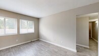 Located at 4233 Jonesboro Rd in Forest Park, GA, this single-floor, 3-bedroom, 1-bathroom unit offers a practical and well-organized layout suited for a variety of living arrangements. The interior is finished with a neutral, warm color palette throughout, creating a clean and cohesive aesthetic.

The kitchen is a standout feature, designed in a galley style with white cabinetry, gray countertops, and black appliances including a range and refrigerator. Light wood-look flooring runs through the kitchen, which connects openly to the rest of the living areas. A window allows natural light to brighten the space.

The living room continues the wood-look flooring and maintains the same neutral tones, offering a simple, versatile area for everyday use. Two hallways provide smooth circulation between rooms throughout the unit.

The three bedrooms feature plush carpeting and neutral walls. The primary bedroom is generously sized, providing ample room for furnishings. Two of the bedrooms include closets with built-in shelving rods, and windows in multiple rooms invite natural light and outdoor views of surrounding greenery.

The bathroom is finished with white tile surrounding a full bathtub and shower combination, complemented by a window for ventilation and natural light. Clean white fixtures complete the space. Overall, the unit offers a straightforward, functional design with consistent finishes throughout.