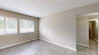 Located at 4233 Jonesboro Rd in Forest Park, GA, this single-floor, 3-bedroom, 1-bathroom unit offers a practical and well-organized layout suited for a variety of living arrangements. The interior is finished with a neutral, warm color palette throughout, creating a clean and cohesive aesthetic.

The kitchen is a standout feature, designed in a galley style with white cabinetry, gray countertops, and black appliances including a range and refrigerator. Light wood-look flooring runs through the kitchen, which connects openly to the rest of the living areas. A window allows natural light to brighten the space.

The living room continues the wood-look flooring and maintains the same neutral tones, offering a simple, versatile area for everyday use. Two hallways provide smooth circulation between rooms throughout the unit.

The three bedrooms feature plush carpeting and neutral walls. The primary bedroom is generously sized, providing ample room for furnishings. Two of the bedrooms include closets with built-in shelving rods, and windows in multiple rooms invite natural light and outdoor views of surrounding greenery.

The bathroom is finished with white tile surrounding a full bathtub and shower combination, complemented by a window for ventilation and natural light. Clean white fixtures complete the space. Overall, the unit offers a straightforward, functional design with consistent finishes throughout.