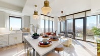 Located in Atlanta's vibrant Midtown neighborhood, this single-floor residence at 770 Juniper St NE offers a refined blend of contemporary design and curated interior details. The open-concept living and dining area is a standout, anchored by dramatic floor-to-ceiling windows that flood the space with natural light and frame sweeping views of the Atlanta skyline. Brass pendant lighting and a crystal chandelier add warmth and sophistication to the entertaining area, which flows seamlessly to a private balcony.

The kitchen is well-appointed with light gray shaker cabinetry, gold hardware, stainless steel appliances, and a large center island with white countertops — ideal for both cooking and casual dining. Light hardwood flooring runs throughout, unifying the home's open floor plan.

The bedrooms offer a serene retreat, each featuring large windows with city views, stylish finishes, and ample natural light. The primary bathroom includes an elongated vanity with backlit mirrors, gold fixtures, large-format tile flooring, and a glass-enclosed shower. A secondary full bath features a tub-shower combination and matching tile work.

A functional mudroom and laundry area with built-in shelving and coat hooks provides excellent organization. The overall ambiance is polished and livable, with an elegant, cosmopolitan character throughout.