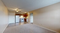 Located at 894 E Old Highway 56 in Olathe, Kansas, this one-bedroom, one-bathroom unit offers a practical and efficiently designed single-floor layout. The open living area features neutral-toned walls, soft carpeting, and a ceiling fan, creating a comfortable and functional space. A window near the entry door allows natural light to brighten the room. The combined dining and kitchen area is equipped with warm wood-toned cabinetry, a full suite of white appliances including a refrigerator, electric range, and dishwasher, complemented by light countertops and durable hard-surface flooring. A pantry provides additional storage within the kitchen area. The bedroom is a well-proportioned private retreat featuring plush carpeting, a natural light source via a window with blinds, and access to multiple closets — three in total throughout the unit — offering generous storage. The bathroom includes a full tub and shower combination, a wood-vanity with a granite-style countertop, a large mirror, and wood-look tile flooring. A hallway connects the main living spaces, contributing to a cohesive and navigable floor plan. Textured ceilings are featured throughout, adding a classic residential character to the home.