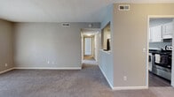 This single-floor residence at 1810 Roswell Rd in Marietta, Georgia offers a well-designed layout with a neutral color palette and a blend of carpet and hardwood-style flooring throughout. The open living and dining area is anchored by an elegant chandelier and connects seamlessly to the kitchen via a pass-through window, creating an airy, communicative flow between spaces. The kitchen is thoughtfully appointed with white shaker-style cabinetry, dark countertops, a white subway tile backsplash, and stainless steel appliances including a refrigerator, dishwasher, and range. A skylight-style ceiling fixture keeps the kitchen bright and functional. The living room features French doors that open to an outdoor area, allowing natural light to pour in. Bedrooms are generously sized with plush carpeting, large windows that invite natural light, and ample wall space. The bathrooms are finished with white cabinetry, dark countertops, and wood-look flooring, with one bathroom featuring a shower-tub combination. A dedicated hallway connects the private areas of the home, providing a clear separation between living and sleeping spaces. Textured ceilings and consistent gray-toned walls contribute to a cohesive, contemporary aesthetic throughout.