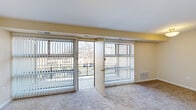 This 2-bedroom, 1-bathroom residence offers a thoughtfully organized single-floor layout designed for comfortable everyday living. The combined living and dining area serves as the heart of the home, featuring plush carpeting, a ceiling fan, and two large sliding glass doors that open to an outdoor balcony, flooding the space with natural light and providing open views of the surrounding neighborhood. The kitchen is efficiently designed with dark cabinetry, light countertops, wood-look flooring, and white appliances including a range and refrigerator. A separate pantry closet adjacent to the kitchen provides additional storage. The primary bedroom is a generously sized retreat featuring two wide windows, a ceiling fan, and soft carpeting, while the secondary bedroom offers its own window for natural light along with a dedicated closet. Three closets throughout the home, including a spacious walk-in with built-in shelving, ensure ample storage throughout. The full bathroom is clean and functional, featuring white cabinetry, a vanity mirror with overhead lighting, white tile wainscoting, and a shower-tub combination. Warm neutral tones carry consistently throughout the space, creating a cohesive and inviting ambiance.