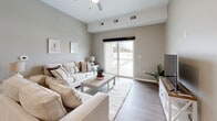 This well-appointed 2-bedroom, 2-bathroom residence in Getzville, NY offers a thoughtfully designed open-concept layout across a single floor. The kitchen serves as a central hub, showcasing white shaker cabinetry, granite countertops, stainless steel appliances, and a spacious island with seating for three — illuminated by stylish pendant lighting. The kitchen flows seamlessly into the living room, which features light hardwood-style flooring, a ceiling fan, and a sliding glass door that invites natural light and outdoor access. Both bedrooms are carpeted and finished in warm neutral tones, providing a calm and restful atmosphere. The generously sized primary bedroom offers ample space for a full furniture arrangement. Each bathroom features granite-topped white vanities and hardwood-style flooring, maintaining a consistent and polished aesthetic throughout. A dedicated laundry room houses a full-size front-loading washer and dryer. Additional storage is provided by a closet. The overall design palette — soft grays, warm beiges, and crisp whites — lends a clean, modern feel that is both functional and welcoming.