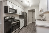 This single-floor residence offers a thoughtfully designed layout that balances comfort and functionality. The open living area is finished with plush carpeting and neutral-toned walls, creating a warm and inviting atmosphere. A sliding glass door leads to a private balcony, filling the space with natural light and providing pleasant outdoor views.

The galley-style kitchen is well-equipped, featuring white shaker cabinetry with brushed nickel hardware, light quartz-style countertops, stainless steel appliances including a refrigerator and dishwasher, a stainless steel sink, and durable wood-look flooring. A ceiling fan adds practicality to the kitchen and dining area.

Both bedrooms are generously sized with soft carpeting, ceiling fans, and ample closet space, including walk-in options. The primary bedroom includes a private en-suite bathroom and an additional closet, offering a comfortable private retreat.

The two full bathrooms are finished with marble-look countertops, white cabinetry, and sleek glass-enclosed tub-shower combinations with chrome hardware. Wood-look flooring extends through both bathrooms, complementing the cohesive aesthetic carried throughout the home. Overall, the space presents a clean, modern feel with consistent finishes and a practical, well-organized floor plan.