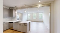 Located at 100 E Chestnut St in Rogers, Arkansas, this thoughtfully designed 2-bedroom, 2-bathroom single-floor unit offers a clean, modern aesthetic throughout. Light hardwood flooring flows seamlessly across every room, creating a bright and cohesive feel.

The open-concept kitchen and living area serve as the heart of the unit. The kitchen is outfitted with gray shaker-style cabinetry, white quartz countertops, a subway tile backsplash, stainless steel appliances, and a central island with a built-in sink and pendant lighting above. A pass-through design connects the kitchen directly to a spacious living area bathed in natural light from multiple windows overlooking greenery.

The generously sized primary bedroom features dual windows, a ceiling fan, and ample closet space. The second bedroom also benefits from a ceiling fan and a bright window with outdoor views. Both rooms carry the same warm hardwood flooring found throughout the unit.

The two bathrooms are finished with gray vanity cabinetry, white quartz countertops, and tub-shower combinations. One bathroom features a tall, narrow window that frames a lush tree view, adding a serene natural touch. Additional conveniences include a dedicated laundry area, a pantry, and three closets, ensuring excellent storage throughout.