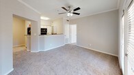 This single-floor residence offers a clean, neutral aesthetic throughout, with warm greige walls and white trim creating a cohesive and inviting atmosphere. The entryway welcomes you with dark hardwood-style flooring that transitions into plush carpet across the main living areas. Crown molding and a ceiling fan with light kit add a polished touch to the open living space, which flows seamlessly into the kitchen via a half-wall breakfast bar. The kitchen is well-equipped with black appliances including a refrigerator, electric range, and over-the-range microwave, complemented by a tasteful mosaic tile backsplash, granite-look countertops, and light wood cabinetry. Both bedrooms are comfortably proportioned, each featuring soft carpet, a ceiling fan, and a window fitted with blinds that allow for natural light and privacy. The bathroom includes dark hardwood-style flooring, a wall-mounted medicine cabinet, brushed nickel fixtures, and a full tub-shower combination with classic white and tan tile surround. Throughout the unit, the consistent neutral palette, practical finishes, and functional layout create a comfortable and move-in-ready living environment.