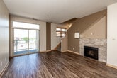 Located at 5465 Mills Civic Pkwy in West Des Moines, Iowa, this two-story residence offers a thoughtfully designed layout spread evenly across both levels. The main floor welcomes you with an open-concept living room featuring rich hardwood-style flooring, a striking stone-surround fireplace, and sliding glass doors that open to a private balcony, flooding the space with natural light and outdoor views. Adjacent to the living area, the kitchen is outfitted with warm maple cabinetry, dark countertops, stainless steel appliances including a dishwasher and range, and hardwood flooring — providing both functionality and style. A hallway connects the main living spaces to a bathroom with tile flooring and wood-tone vanity cabinetry. The dedicated laundry room houses a stacked washer and dryer unit with tile flooring for easy maintenance. Upstairs, the second floor features carpeted bedrooms bathed in natural light from multiple windows, offering a comfortable and quiet retreat. A spacious walk-in closet is outfitted with extensive built-in shelving, hanging rods, and drawers, maximizing storage efficiency. Three bathrooms throughout the home include clean, modern finishes such as glass-enclosed showers with brushed nickel hardware. The overall ambiance is bright, functional, and well-organized.