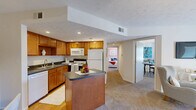 Located at 6650 Creek Bay Dr in Indianapolis, Indiana, this single-floor, two-bedroom, one-bathroom residence offers a practical and comfortable layout. The open-concept kitchen is well-appointed with warm wood cabinetry, dark granite-style countertops, a central island, hardwood flooring, and a full suite of white appliances including a dishwasher, range, microwave, and refrigerator. The kitchen flows naturally into a combined dining and living area, where plush carpet underfoot and a sliding glass door lead to a private patio, filling the space with natural light and outdoor views. The dining area features a pendant light fixture overhead and neutral walls that create a welcoming atmosphere. The living room provides a relaxing retreat with carpet flooring and understated finishes. The primary bedroom offers a comfortable footprint with carpet, a closet, and a textured ceiling. The second bedroom, also carpeted, includes a window and ample space for various uses. The shared full bathroom features hardwood flooring, wood vanity cabinetry with a granite-style countertop, and a tub/shower combination. Additional highlights include four closets, a dedicated laundry area, and a utility room, ensuring generous storage and functional convenience throughout.