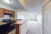 Located at 501 Plantation St in Worcester, MA, this two-bedroom, two-bathroom residence offers a functional and well-organized single-floor layout. The open-concept kitchen flows seamlessly into the living area, creating a connected and spacious feel. The kitchen is equipped with warm wood cabinetry, granite-style countertops, black appliances including an electric range and dishwasher, and a peninsula that serves as both a prep area and a casual dining space. Wood-look flooring grounds the kitchen, while plush carpeting extends throughout the living room and bedrooms. The expansive living area is bathed in natural light from a large window and includes a wall-mounted air conditioning unit. The generously sized primary bedroom features a sliding glass door opening to a private balcony with scenic tree-line views, providing a bright and airy retreat. The second bedroom is comfortably sized with easy closet access. A dedicated walk-in closet with built-in wire shelving offers ample storage. Both bathrooms are finished with wood-look tile flooring, warm wood vanities, white countertops, and full tub-shower combinations, presenting a clean and consistent aesthetic throughout the residence.