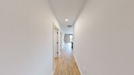 This thoughtfully designed single-floor residence offers 2 bedrooms and 3 bathrooms across a spacious, open-concept floor plan. Light hardwood flooring runs throughout the home, complemented by crisp white walls and recessed lighting that create a bright, contemporary atmosphere.

The kitchen is a standout feature, boasting white shaker cabinetry, a classic subway tile backsplash, stainless steel appliances, and a large central island with a white quartz countertop and seating for multiple guests, illuminated by bold black pendant lights. The kitchen flows seamlessly into the dining area, which opens to an outdoor balcony through full-height sliding glass doors — ideal for indoor-outdoor living.

The living room features large black-framed windows that frame urban cityscape views, flooding the space with natural light. Both bedrooms are generously sized with oversized black-framed windows offering sweeping city views. The primary bedroom includes a dedicated walk-in closet with built-in shelving.

The bathrooms are finished with neutral tile flooring, dark wood cabinetry, white quartz countertops, and sleek black fixtures. A utility room and additional closet provide practical storage. A clean hallway with recessed lighting connects all rooms, reinforcing the home's modern, cohesive design aesthetic.