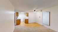 Located at 1956 W Alexis Rd in Toledo, Ohio, this 2-bedroom, 1-bathroom unit offers a practical and well-organized single-floor layout. The open-concept living and kitchen area creates a cohesive, functional space, with light hardwood flooring in the kitchen transitioning to plush carpet in the living room. A ceiling fan with light kit adds comfort overhead, while a sliding glass door in the living area provides access to the outdoors and brings in natural light.

The kitchen is efficiently designed with warm wood cabinetry lining both sides, a double-basin sink, a dishwasher, a coil-top electric range with overhead ventilation, and a full-size refrigerator. A skylight panel in the kitchen ceiling enhances brightness throughout the space.

Both bedrooms are carpeted and feature neutral walls with textured ceilings. The primary bedroom is generously sized and includes a dedicated closet with built-in shelving for organized storage. The second bedroom, also carpeted, offers a tall window with a view of surrounding greenery, providing natural light and a pleasant outlook.

The bathroom includes a white-tiled walk-in shower with a built-in shelf and safety grab bar. Hallways connect the rooms efficiently, with multiple closets providing ample storage throughout the unit.