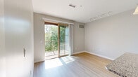 Located at 30 Traders Row in historic Salem, MA, this thoughtfully designed one-bedroom, one-bathroom residence offers a clean, modern aesthetic throughout. Light-toned hardwood flooring flows through the main living areas, complemented by neutral gray walls that create a bright and airy atmosphere. The galley-style kitchen is well-equipped with granite countertops, shaker-style cabinetry, a stainless steel sink, and a full suite of stainless steel appliances, including a range, microwave, and dishwasher. The living area opens directly onto a private balcony through sliding glass doors framed in warm wood tones, flooding the space with natural light and offering pleasant outdoor views of surrounding greenery. The bedroom features plush wall-to-wall carpeting, a generously sized window with wooded views, and access to a spacious walk-in closet outfitted with wire shelving for organized storage. A second closet provides additional flexibility. The bathroom is finished with large-format tile flooring and a granite-topped vanity. A dedicated in-unit laundry closet with a stacked washer and dryer adds everyday convenience. Track lighting in the living area enhances the modern, functional design of this well-appointed Salem residence.