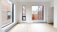 Located on Rue Sherbrooke Ouest in Montréal, this single-floor unit offers three bedrooms, one bathroom, a kitchen, and a closet within a well-organized layout. The interior is finished in a clean, modern aesthetic, with light wood flooring running throughout and crisp white walls that enhance the sense of brightness.

The kitchen is a functional and stylish centerpiece, featuring white cabinetry, dark countertops, a black tile backsplash, and stainless steel appliances including a range and refrigerator. A peninsula counter provides additional workspace and visual separation from the adjacent corridor.

Each bedroom is bathed in natural light courtesy of large, black-framed windows that frame views of Montréal's surrounding urban architecture. The primary bedroom is a well-proportioned space with generous windows on two walls, offering an expansive city outlook. The additional bedrooms also benefit from large operable windows and warm wood flooring.

The bathroom is finished with white subway wall tiles, a small-format white tile floor, and a spacious glass-enclosed walk-in shower. The hallway connecting the rooms is clean and uncluttered, with practical touches such as a wall-mounted thermostat.

Overall, the unit presents a modern, minimalist character with consistent finishes, abundant natural light, and functional room configurations throughout.