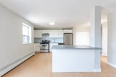 Located at 446 Kerr St in Oakville, Ontario, this one-bedroom, one-bathroom unit offers a well-organized single-floor layout designed for comfortable everyday living. The open-concept kitchen and living area form the heart of the space, finished with warm light hardwood flooring that extends throughout. The kitchen is equipped with stainless steel appliances — including a refrigerator, gas range, and dishwasher — complemented by white cabinetry, a neutral tile backsplash, and a peninsula that provides additional counter space and separates the cooking area from the living room. The living room is bright and airy, benefiting from a large sliding glass door that opens onto a private balcony with views of the surrounding greenery, allowing natural light to fill the room. The bedroom is a comfortable size, featuring a double closet with bi-fold doors, a window overlooking the exterior, and baseboard heating. The bathroom is clean and functional, with a vanity, mirror, tile flooring, and towel bar. Neutral grey walls, white trim, and consistent flooring throughout give the unit a cohesive, modern feel. Baseboard heaters are present in multiple rooms, ensuring efficient climate control across the entire space.