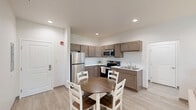 This 2-bedroom, 3-bathroom unit in Angola, Indiana offers a practical and comfortable single-floor layout designed for everyday living. The open-concept kitchen and living area serves as the heart of the unit, featuring warm-toned cabinetry, stainless steel appliances including a refrigerator, range, and over-the-range microwave, light countertops, and a double-basin sink. Recessed lighting illuminates the space, which flows seamlessly into the dining area and a well-sized living room. The living room benefits from natural light through a window dressed with white curtains, creating a bright and welcoming atmosphere. Light hardwood-style flooring runs consistently throughout the unit, lending a clean, cohesive aesthetic. The primary bedroom is generously proportioned, offering a window with natural light and ample room for furnishings. The second bedroom maintains a similarly comfortable and serene character. Three bathrooms serve the unit, including one featuring a shower-tub combo and another conveniently located near an in-unit stacked washer and dryer. Neutral white walls throughout contribute to a fresh, move-in-ready feel. A hallway and closet provide additional storage and circulation, rounding out this efficiently designed residential unit.
