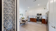 Located at 328 Cherokee Blvd in Chattanooga's vibrant North Shore neighborhood, this single-floor residence offers a thoughtfully designed open layout with modern finishes throughout. The kitchen is a standout feature, showcasing a two-tone cabinetry design with rich walnut lower cabinets paired with crisp white upper cabinets extending to the ceiling, complemented by a classic subway tile backsplash, white quartz countertops, and stainless steel appliances. Light hardwood-style flooring flows seamlessly from the kitchen into the adjacent dining area, creating a cohesive and airy feel. The living room is bright and inviting, anchored by large sliding glass doors that provide direct balcony access and generous views of the surrounding streetscape and greenery, flooding the space with natural light. The bedroom is a calm retreat, featuring plush carpeting, a ceiling fan, and a window that allows natural light and outdoor views. The bathroom is finished in clean, neutral tones with white cabinetry, a large vanity mirror, and tile flooring. A dedicated laundry area with a full-size washer and dryer adds everyday convenience, while an additional closet provides practical storage. The overall ambiance is clean, contemporary, and comfortable throughout.