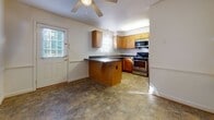 Located at 66 Lakeshore Dr in Hampton, Virginia, this two-story home offers a practical and well-organized layout across both levels. The main floor features a kitchen equipped with warm-toned wood cabinetry, dark countertops, stainless steel appliances including a range, microwave, and refrigerator, and a peninsula that provides additional prep and seating space. Tile flooring runs throughout the kitchen, and a ceiling fan with a door providing exterior access adds to the room's functionality. A stacked washer and dryer unit is conveniently housed in a dedicated laundry area on this level. A half bathroom with tile flooring, a wood vanity, and a angled ceiling detail is also found on the main floor.

The upper level features carpeted rooms filled with natural light from large windows with exterior views of surrounding greenery. A generously sized bedroom includes multiple closets with built-in rods, offering ample storage. A full bathroom on this level is outfitted with tile flooring and a full tub-shower combination. A staircase with dark wood balusters connects the two floors, contributing to the home's overall cohesive and clean aesthetic throughout.