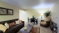 Located at 1699 Shanley Dr in Columbus, Ohio, this single-floor residence offers a practical and comfortable layout designed for everyday living. The combined living and dining area serves as the heart of the home, providing an open and cohesive space that maximizes usability. Soft, neutral wall tones in warm beige create a welcoming ambiance throughout, complemented by wall-to-wall carpeting that adds warmth underfoot. The living area accommodates a full seating arrangement, with ample room for a sofa, accent chair, and coffee table, making it well-suited for relaxing or entertaining. Transitioning seamlessly from the living space, the dining area offers enough room for a dining table and chairs, ideal for everyday meals. Baseboard heating is visible along the walls, ensuring consistent warmth during colder months. The space is illuminated by a combination of natural light and interior lighting, including a floor lamp that contributes to the room's cozy atmosphere. Decorative touches such as area rugs and accent plants enhance the overall aesthetic. The single-floor design ensures easy accessibility and convenient navigation throughout the home, making it a straightforward and functional living space in a residential Columbus neighborhood.