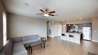 This single-floor unit is designed with a practical, modern aesthetic and an open-concept layout that connects the living area directly to the kitchen. The living room features wood-style flooring, neutral-toned walls, and multiple windows fitted with horizontal blinds that allow natural light to filter through. A ceiling fan with an integrated light fixture serves as a functional focal point overhead. The kitchen is well-appointed with dark espresso cabinetry, granite countertops, and a full suite of stainless steel appliances, including a refrigerator, range, and microwave. A central island with seating for two provides additional workspace and casual dining space, illuminated by pendant lights above.

The bedrooms are carpeted for comfort and each includes a ceiling fan, window with blinds, and closet access. The rooms maintain the same neutral color palette found throughout the unit, contributing to a cohesive, understated feel.

Two full bathrooms are present, each featuring dark wood vanity cabinetry, a white countertop with an integrated sink, a large mirror with overhead lighting, and a tub-shower combination. Wood-style flooring runs through both bathrooms, tying them visually to the rest of the unit.