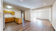 Located at 24 Eighth St N in Fargo, North Dakota, this 2-bedroom, 2-bathroom unit offers a practical and well-appointed single-floor layout. The open-concept kitchen and living area serves as the heart of the space, featuring warm honey-toned wood cabinetry, a peninsula with counter seating, stainless steel appliances including a refrigerator, range, and microwave, and durable hardwood-style flooring that extends throughout. A ceiling fan adds comfort to the combined living area, which receives natural light from a window overlooking the exterior.

Both bedrooms are comfortably sized, with one featuring plush carpeting and a window with blinds, and the other showcasing a distinctive herringbone-patterned hardwood-style floor with natural light and baseboard heating. A dedicated closet provides additional storage.

The two bathrooms are cleanly finished — one features a full tub-shower combination with a wood-toned vanity and tile flooring, while the other includes a standalone walk-in shower alongside built-in wire shelving for organized storage. Baseboard heating is present throughout the unit, ensuring consistent warmth. The textured ceilings and neutral wall tones create a clean, functional aesthetic throughout this Fargo residence.