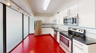 Located at 110 Campbell Ave SW in downtown Roanoke, Virginia, this one-bedroom, one-bathroom unit offers a well-organized layout across a single floor. The kitchen is a standout feature, showcasing bold red flooring, crisp white cabinetry, dark countertops, and a full suite of stainless steel appliances including a refrigerator, electric range, microwave, and dishwasher. A decorative tile backsplash accent adds a modern touch, while a sliding glass partition provides a stylish separation from the adjacent living area. The bedroom offers a comfortable, private retreat with parquet-style tile flooring, a ceiling fan with light fixture, and dark-trimmed door and baseboards that contrast cleanly against neutral walls. The bathroom is finished with large-format light tile flooring, a full soaking tub with shower, and a dark-vanity sink, with a stacked washer and dryer conveniently located just outside for in-unit laundry access. A connecting hallway ties the spaces together efficiently. The overall aesthetic blends contemporary finishes with functional design, creating a practical and visually cohesive living environment in the heart of Roanoke.