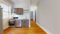 Located at 487 Prentis St in Detroit's Midtown neighborhood, this efficiently designed one-bedroom, one-bathroom unit offers a well-organized layout across a single floor. Warm hardwood flooring runs continuously throughout the space, lending a cohesive and inviting feel.

The updated kitchen is a standout feature, showcasing rich dark-stained wood cabinetry, open shelving, a herringbone-patterned white tile backsplash, light countertops, and a full suite of stainless steel appliances including a range, dishwasher, and refrigerator. A window above the counter brings in natural light, and baseboard heating ensures year-round comfort.

A hallway connects the kitchen area to the bedroom and bathroom, providing a clear and functional flow through the unit. The bedroom is a cozy, well-proportioned room with light gray walls, hardwood floors, and baseboard heating. Its clean, neutral palette offers a versatile canvas for personalization.

The bathroom features classic full white subway tile surrounding a soaking bathtub, with a window that allows natural light to filter in. The tiling provides a clean, timeless aesthetic. Overall, the unit presents a practical and updated living space with consistent finishes and a straightforward, efficient layout suited for single occupancy.