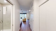 Located at 945 Mid City Dr in Huntsville, Alabama, this efficiently designed studio offers a thoughtful single-floor layout that maximizes every square foot. Rich hardwood-style flooring runs throughout the main living area, connecting the open living space to the well-appointed kitchen and private sleeping area. A ceiling fan overhead and large floor-to-ceiling windows flood the living space with natural light and offer views of the surrounding area, creating an airy, welcoming ambiance.

The kitchen is a standout feature, outfitted with light wood cabinetry, open industrial-style shelving, a tile backsplash, stainless steel appliances including a full-size refrigerator and electric range, and a sleek undermount sink with a matte black faucet — providing full functionality in a compact footprint.

The sleeping area is bright and neatly proportioned, with clean white walls, a ceiling fan, and warm lighting that contributes to a calm, restful atmosphere. The bathroom is finished in crisp white large-format tile, complete with a glass-enclosed walk-in shower and a wood-accented vanity for a modern, clean aesthetic. A dedicated closet and in-unit laundry add practical convenience. The overall design reflects a contemporary, minimalist style well-suited for efficient urban living.