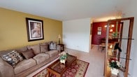 This single-floor residence offers a thoughtfully designed layout with a warm and cohesive interior aesthetic. The living room serves as the heart of the home, featuring soft carpeting, bold golden-yellow accent walls, and a large sliding glass door that invites natural light and provides access to an outdoor balcony area. The open flow connects seamlessly to the dining area, which is distinguished by a rich burgundy accent wall, an elegant chandelier, and a decorative wrought iron room divider that adds a striking architectural detail.

The kitchen is well-equipped with dark wood cabinetry, a stainless steel gas range, a full-size refrigerator, and a double basin sink, all finished with tile flooring for easy maintenance. A contrasting burgundy accent wall adds a bold touch.

The primary bedroom is generously sized with plush carpeting, a window with natural light, and a coordinating burgundy accent wall. A second bedroom offers a bright, cheerful atmosphere with ample natural light through a large window and soft carpet underfoot.

The bathroom is finished with classic white tile, a tub-shower combination, and a vanity with mirror. Throughout the residence, the consistent use of warm accent colors, carpet, and decorative details creates an inviting and cohesive living environment.
