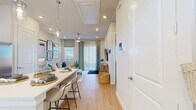 Located at 151 S Buddy Hayes Blvd in Anna, TX, this one-bedroom, one-bathroom single-floor unit offers a thoughtfully designed open-concept layout that maximizes every square foot. Light wood-tone flooring flows seamlessly throughout, creating a warm and cohesive aesthetic across all rooms.

The kitchen is a standout feature, outfitted with white shaker cabinetry, stainless steel appliances including a refrigerator, dishwasher, and range, subway tile backsplash, and a generous white breakfast bar with seating — ideal for casual dining. A pantry provides additional storage convenience.

The living room is bright and welcoming, with large sliding glass doors that allow abundant natural light and provide access to the outdoors. A ceiling fan, recessed lighting, and neutral walls contribute to the airy atmosphere.

The bedroom is a comfortable and serene retreat, featuring windows with blinds, warm neutral tones, and access to a dedicated closet. The full bathroom offers a long vanity with white cabinetry and ample counter space, a glass-enclosed shower, and light wood-look flooring that ties the space together.

Smart home technology is visible throughout, and the clean, modern design makes this unit a well-appointed and functional residence in Anna, TX.