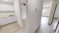 This 1-bedroom, 1-bathroom unit in Calgary, Alberta offers a clean, functional layout across a single floor. Light-toned hardwood flooring runs throughout the entire space, creating a cohesive and airy feel that enhances the brightness of each room.

The living room is the most spacious area of the unit, featuring a large window that invites natural light and provides outdoor views. A baseboard heating unit runs along the exterior wall, ensuring year-round comfort. The textured ceiling adds a classic character to the room, which offers generous wall space adaptable to a variety of furniture arrangements.

The kitchen is efficiently designed with white cabinetry and countertops, offering practical storage and workspace. A ceiling fan fixture in the adjacent area provides additional air circulation. A wall-mounted intercom panel is conveniently located near the entry, along with easy access to the living and kitchen zones.

The bedroom is a well-proportioned private retreat, featuring a window with curtains that allow for light control and privacy. A baseboard heater runs below the window, and the textured ceiling carries through from the living area, maintaining a consistent aesthetic throughout.

The bathroom is neatly finished with light beige tile surrounding the full bathtub and shower combination, complemented by a white vanity and light hardwood-style flooring, offering a clean and functional space.