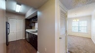 This single-floor 1-bedroom, 1-bathroom residence offers a practical and comfortable layout designed for everyday living. The kitchen is efficiently arranged with dark espresso cabinetry, light countertops, stainless steel appliances including a refrigerator and electric range, a built-in dishwasher, and hardwood-style flooring. A louvered pantry door provides convenient storage within the kitchen corridor. The living area is generously sized, finished with plush carpeting, and features a chandelier overhead along with French doors that invite natural light and provide access to the outdoors. A chair rail detail along the walls adds a subtle architectural touch. The bedroom is a comfortable retreat, carpeted and bright with a window overlooking the exterior, and is equipped with a ceiling fan and light fixture. The bathroom is well-appointed with dark cabinetry, a wide vanity with a single sink, a large mirror spanning the length of the counter, a tall storage tower cabinet, and hardwood-style flooring. A textured ceiling is consistent throughout the residence. Overall, the space offers a cohesive design with functional finishes and a warm, understated ambiance suited for comfortable daily living.